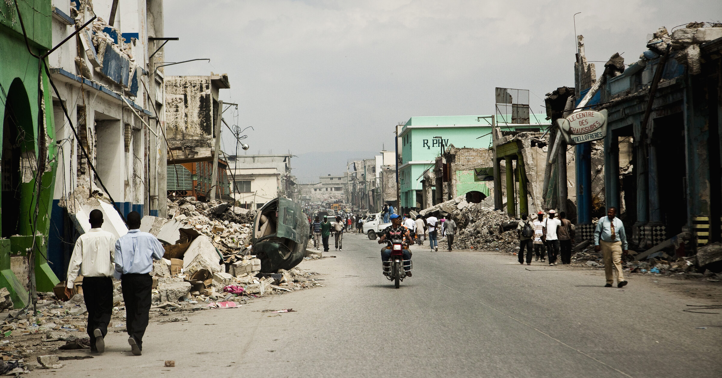 People walking a rubble-lined street after the earthquake