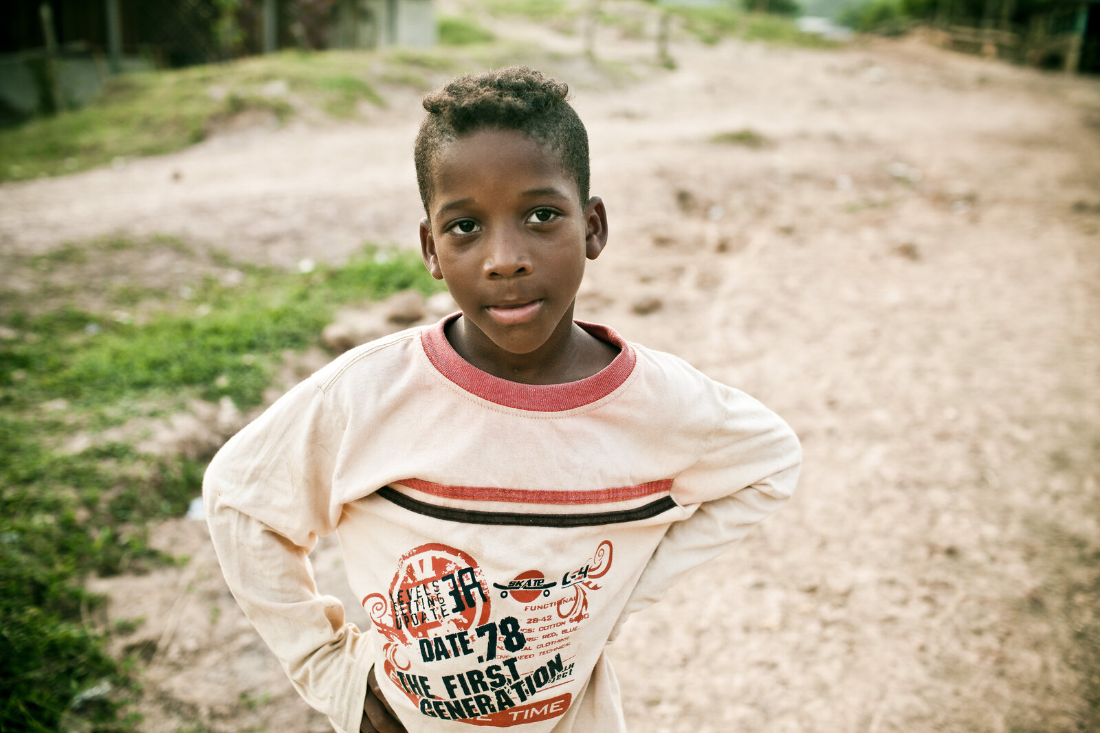 A young boy standing with hands on hips, looking squarely at the camera