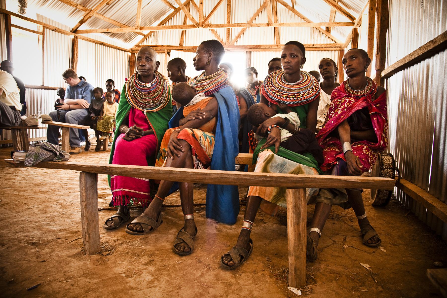 A community gathered together under a wooden shelter