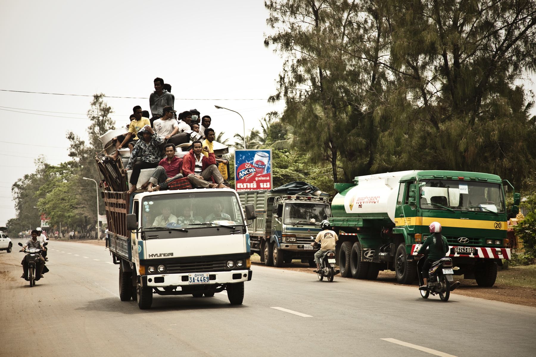 Overloaded trucks and motorbikes on a busy highway