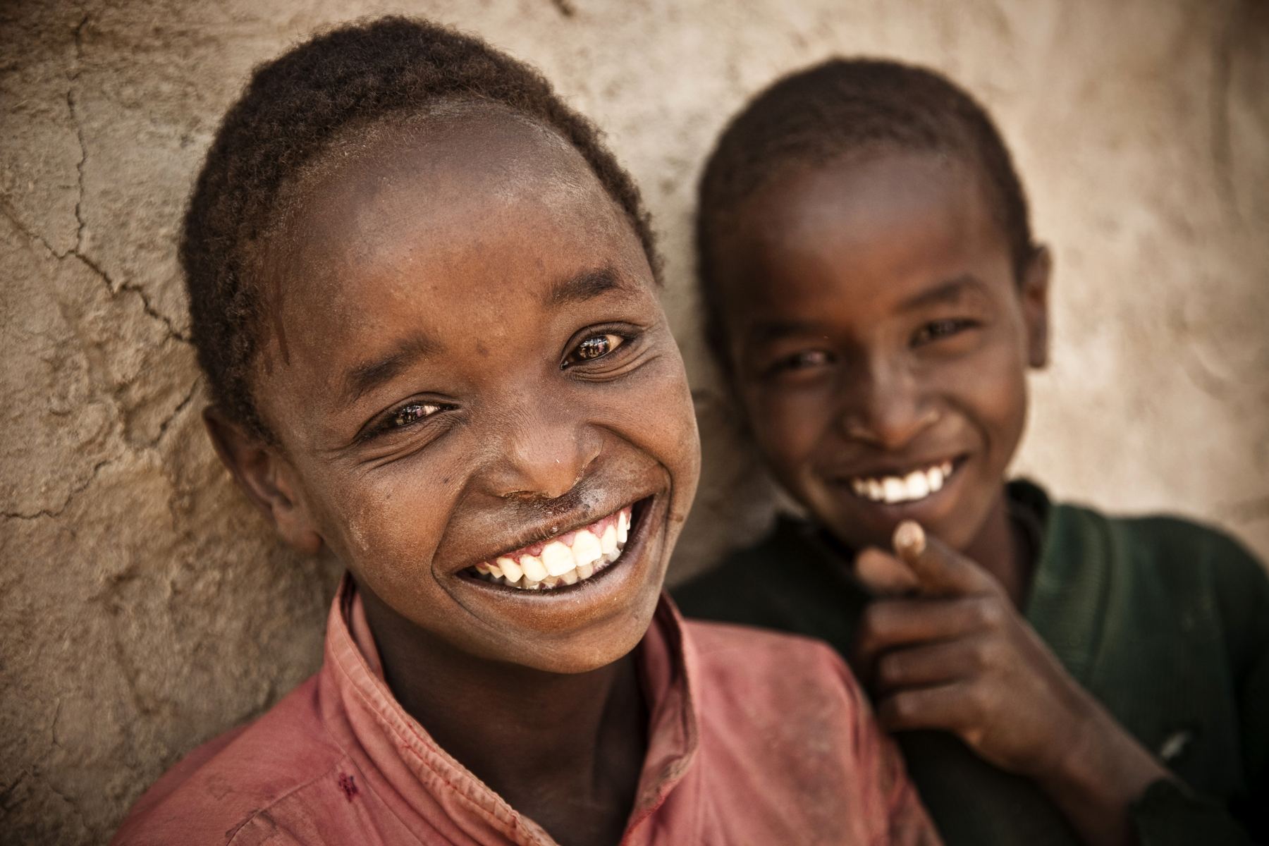 Two children laughing together in bright sunlight