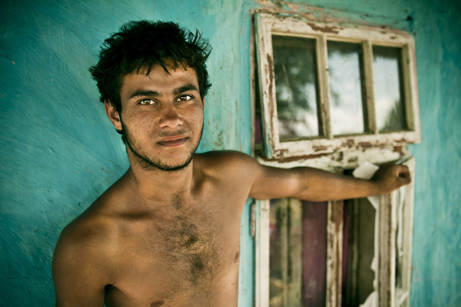 A young man leaning in a turquoise doorway