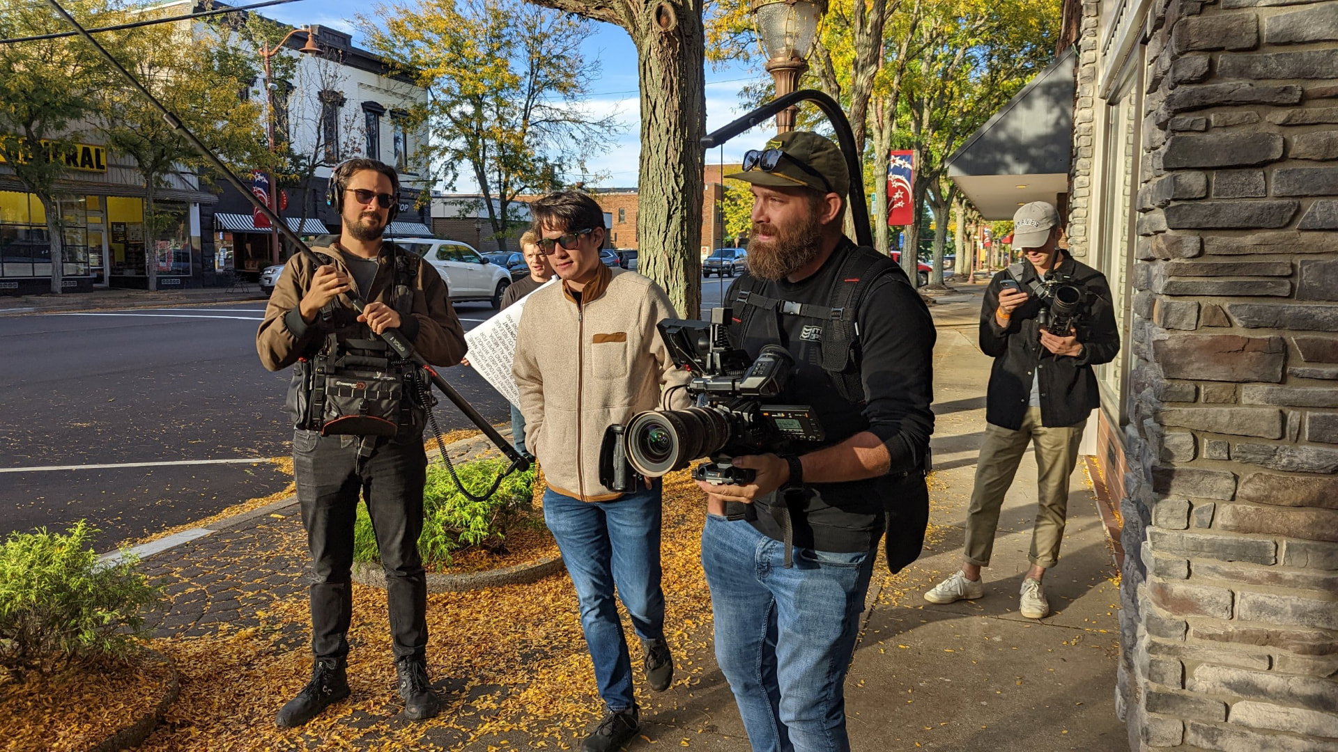Whisper documentary crew filming on a small-town street in autumn